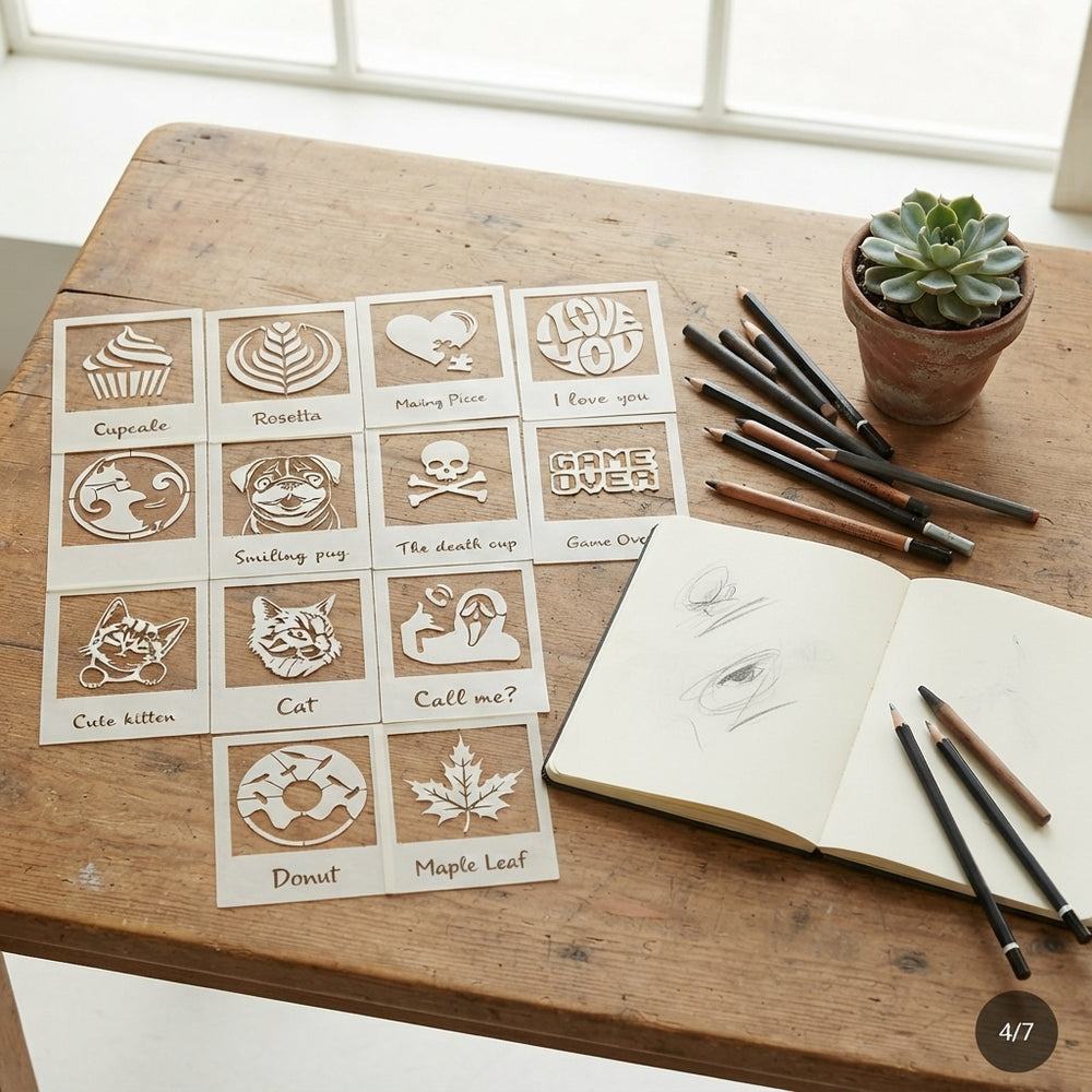 A collection of 12 art stencils arranged on a wooden table with drawing supplies and a small potted plant.
